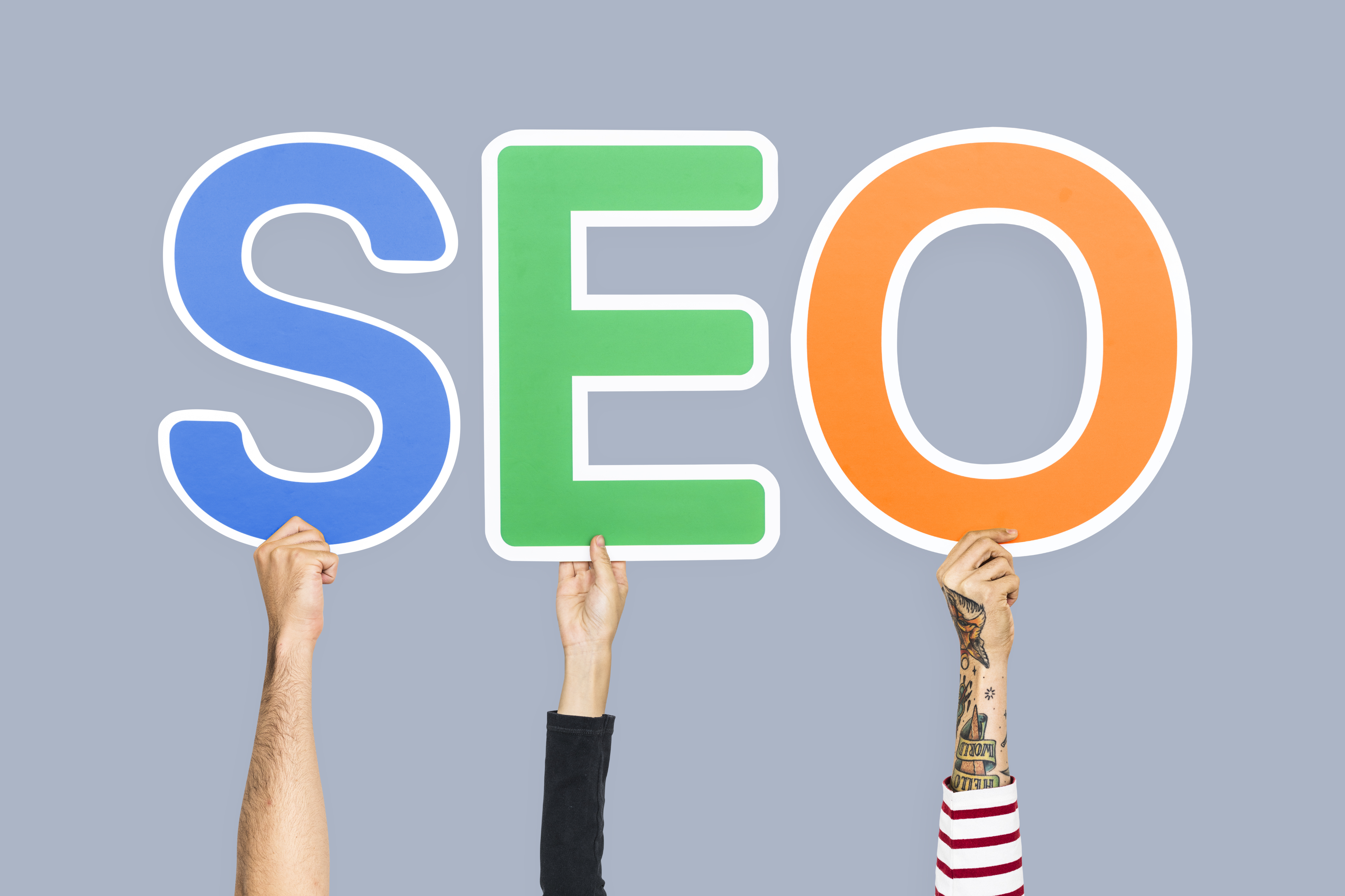 Hands holding up colorful letters forming the abbreviation  SEO